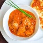 Shrimp curry masala with ginger, garlic, tomato in a white bowl, garnished with green onions.